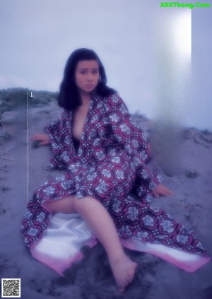 A naked woman sitting on a purple background.