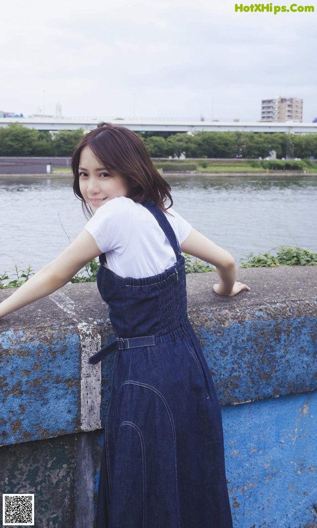 A woman leaning against a wall by the water.