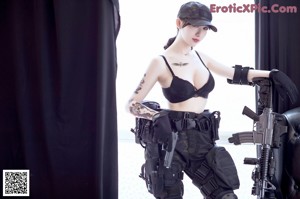A woman in a black outfit holding a gun.