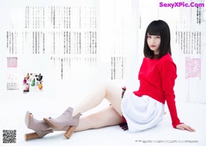 A woman in a red sweater and plaid skirt posing for a picture.