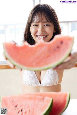 A woman in a white bikini eating a slice of watermelon.