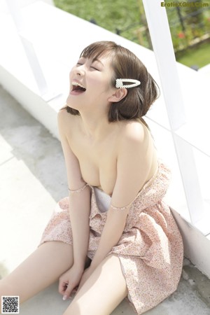 A woman sitting on the grass holding an umbrella.