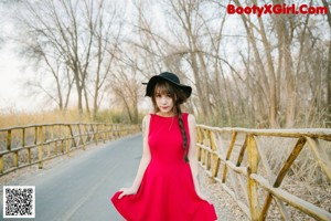 A woman in a nude bodysuit leaning against a tree.