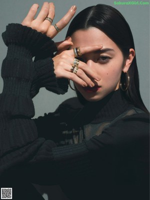 A woman wearing a black turtle neck sweater and a green ring.