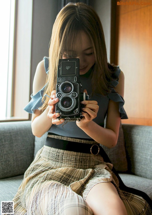 A woman sitting on a couch holding a camera.