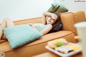 A woman sitting on a window sill holding a bag of chips.