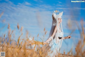 A woman in a white dress holding a bunch of wheat.