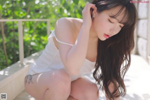 A woman in a white tank top posing for the camera.