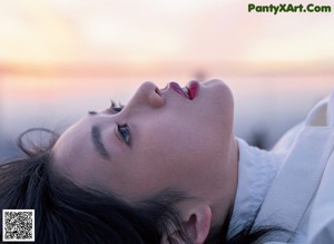 A woman with black hair wearing a white shirt.