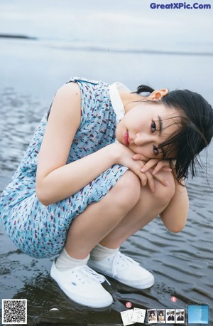 A woman in a colorful dress leaning against a window.