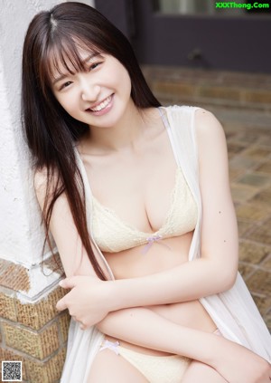 A woman in a white blouse and black panties posing on a couch.