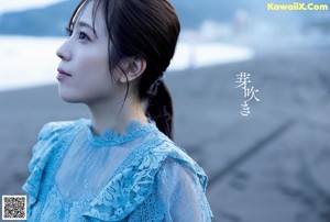 A woman in a blue dress standing on the beach.