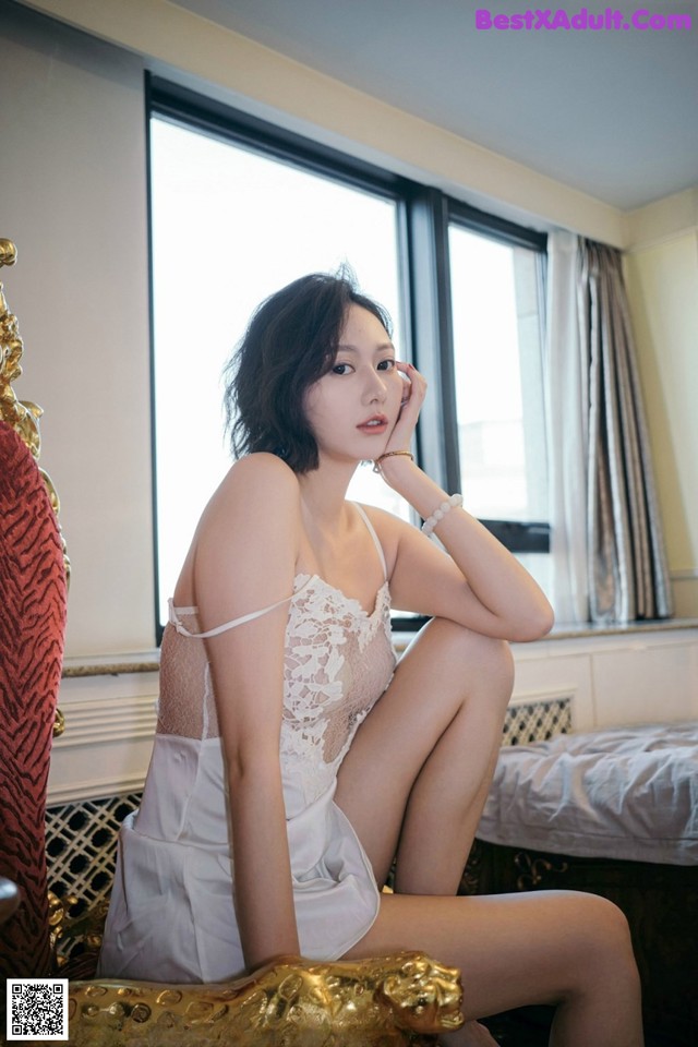 A woman sitting on top of a bed next to a window.
